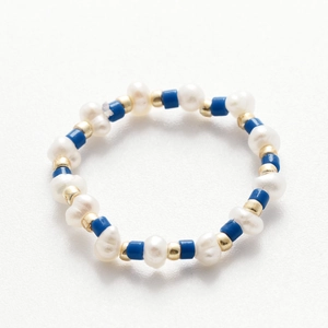 Dettaglio di un anello fatto a mano con perle d'acqua dolce bianche e perline blu a tubo