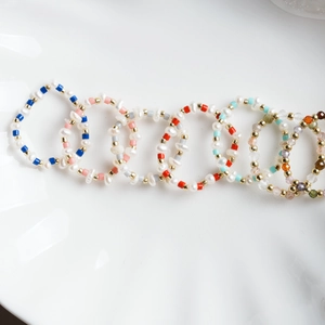 Dettaglio macro di anelli artigianali in perle d'acqua dolce con cristalli colorati