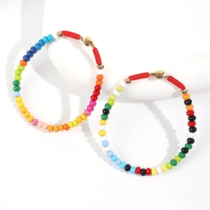 Detail of colorful enamel beaded bracelets with red woven cords and golden metal clasps