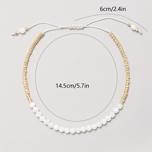 Detalle de la pulsera bohemia de cuentas blancas con acentos dorados y cordón ajustable