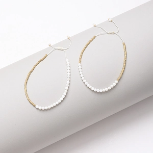 Detalle de pulsera bohemia de cuentas y tubos dorados con cordones tejidos ajustables