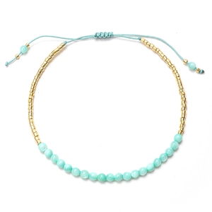 Detalle de pulsera ajustable de cuentas azules con detalles dorados y cierre de cordón