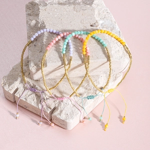 Detalle de pulseras bohemias ajustables con cuentas pastel sobre exhibidor de piedra