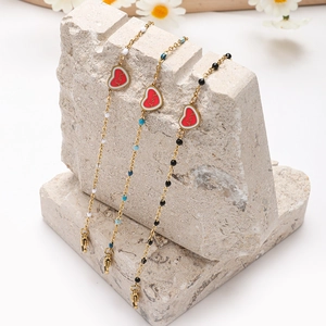 Gouden armbanden met Love-harthanger en kralen in wit, blauw en zwart