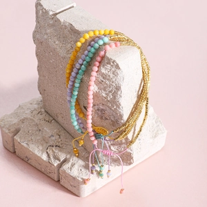 Vista detallada de cuatro pulseras bohemias de cuentas de colores sobre una piedra