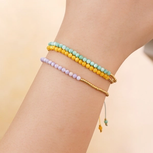 Detalle de pulseras bohemias de cuentas apiladas en verde menta, amarillo y lila suave