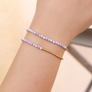 Primer plano de pulseras minimalistas de cuentas lavanda con detalles en tono dorado