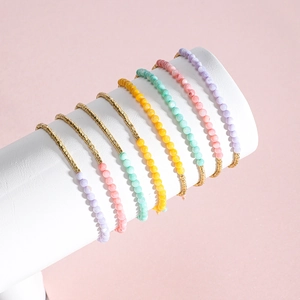 Detalle de un conjunto de siete pulseras bohemias con cuentas moradas y detalles dorados