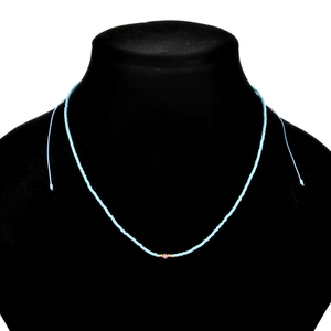 Detail of light blue beaded necklace with pink gem accent on a black neck display