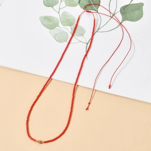 Detail of red beaded necklace with pink bead accent and adjustable cord tie closure