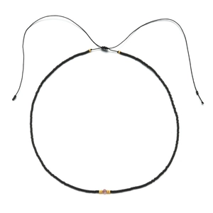 Detail of adjustable black beaded necklace featuring a pink crystal and gold metal accents