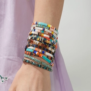 Close-up of Bohemian layered Tila bead bracelets featuring colorful geometric patterns
