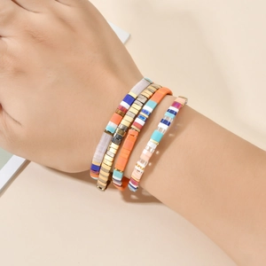 Détail de bracelets bohèmes empilables en perles Tila au poignet avec des couleurs vives