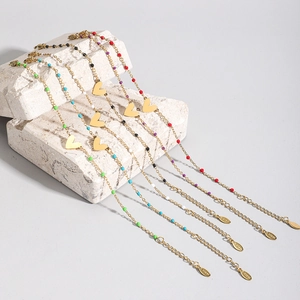 Dettaglio di bracciali con cuore in acciaio inossidabile e perline in cinque colori
