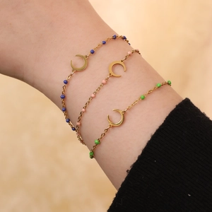 Detailed view of layered gold-tone crescent moon bracelets with blue pink and green beads