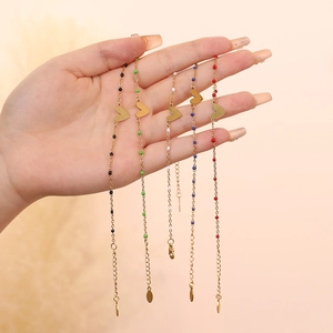 Dettaglio dei bracciali con ciondolo a cuore, perline colorate e catena placcata oro