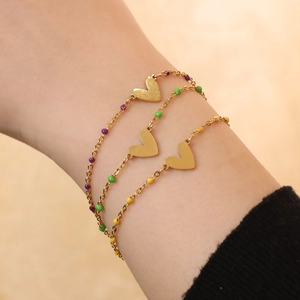 Dettaglio di tre braccialetti a cuore dorati con perline colorate e ciondolo in metallo spazzolato