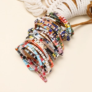 Detailed side view of colorful bohemian Tila bead bracelets on a wooden display stand
