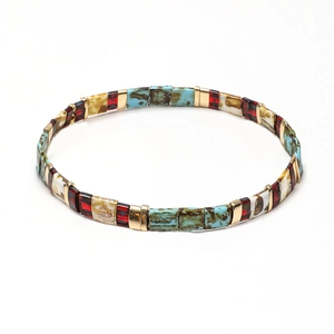 Bohemian style stretch bracelet with colorful Tila beads and gold accents on white base