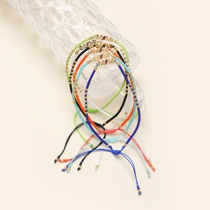 Détail de bracelets en perles colorées avec pendentif MOM sur un flacon en verre
