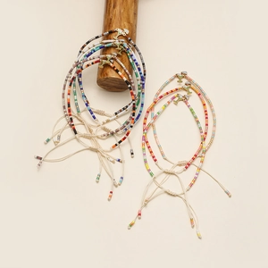 Detalle de pulseras de cuentas MIYUKI con dije de cóctel y cordón bohemio tejido de color
