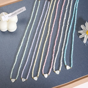 Dettaglio macro di collane di perle fatte a mano con ciondoli a cuore bianco multicolore