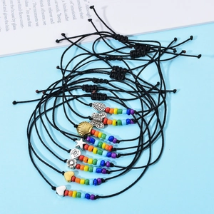 Dettaglio di braccialetti con perline colorate e ciondoli su sfondo azzurro chiaro