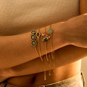 Gros plan de bracelets en perles Miyuki avec œil maléfique et breloques cœur au poignet