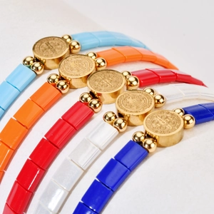Close-up of colorful Tila bead bracelets with gold San Benito religious medals and beads