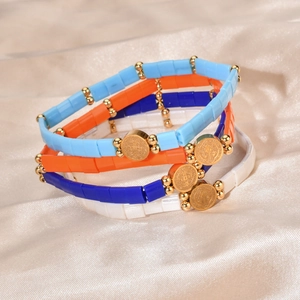 Bohemian Tila bead bracelets with San Benito medal charms on champagne silk fabric