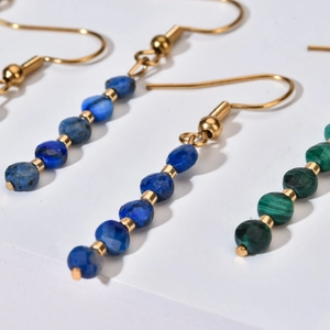 Detailansicht der Perlenohrringe mit blauen und grünen Steinen sowie goldenen Elementen