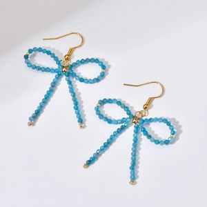 Detail of handmade blue beaded bow earrings with gold-tone hooks and faceted texture