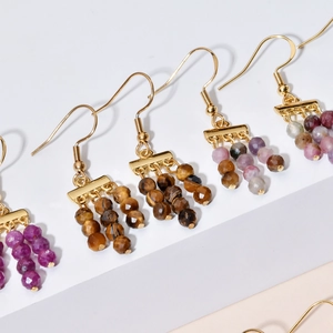 Detail of bohemian handmade beaded earrings with gold hooks and multi-color stone drops