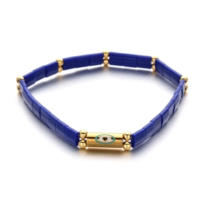 Detail of blue Tila beads bracelet with a gold-plated evil eye charm and spacer beads