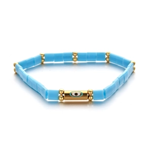 Bohemian sky blue beaded evil eye bracelet with golden metal spacers on white background