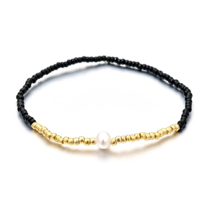 Pulsera elástica bohemia con cuentas negras, detalles dorados y perla blanca
