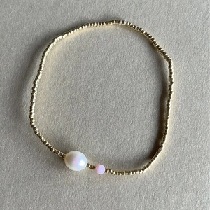 Bracelet perlé doré bohème minimaliste avec une grande perle blanche et touche rose