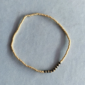 Bracciale di perline minimalista con perline dorate e accenti di spinello nero in cerchio