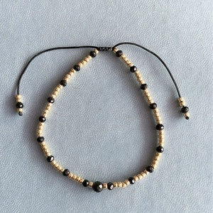 Bracciale regolabile con perle di spinello nero e oro con cordino intrecciato