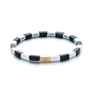 Detalle de la pulsera elástica de esmalte blanco y negro con cierre de metal dorado pulido