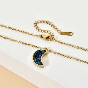 Close-up of golden crescent moon necklace with blue crystal inlay and S.STEEL stamp detail