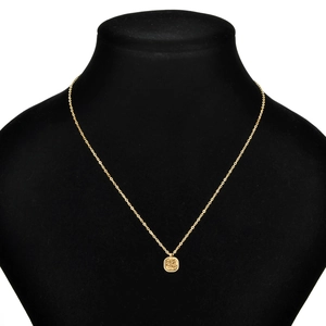 Detail of square gold pendant with frosted sand texture on a black display bust