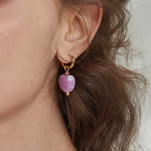 Close-up of a purple marble heart pendant earring worn on a model with golden metal accents