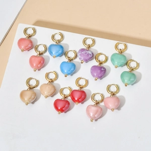 Close-up showing a colorful variety of heart-shaped glazed ceramic pendant hoop earrings