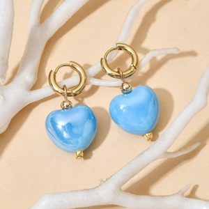 Detailed close-up of blue marble ceramic heart earrings with gold ring hooks