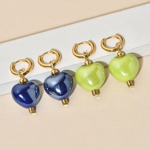 Detailed view of heart-shaped earrings in dark blue and yellow-green on a display stand