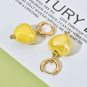 Macro shot of yellow heart-shaped ceramic charms on golden hoops for elegant styling