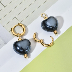 Detail showing gold hoop earrings with detachable heart-shaped grey ceramic pendants