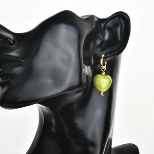 Detail view of a gold hoop earring with a vibrant grass green heart ceramic pendant