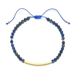 Detail eines Lapislazuli Perlenarmbands mit einem polierten goldenen Metallrohr